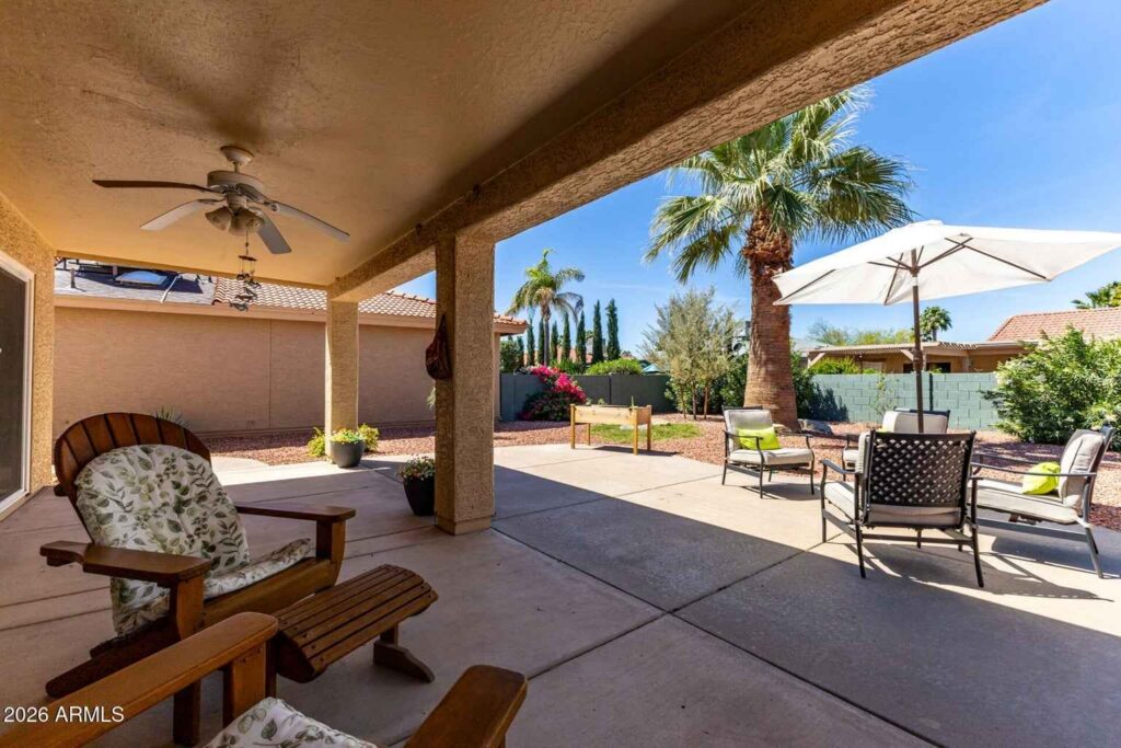 Covered patio in Sun Lakes AZ home overlooking fenced backyard and desert landscaping