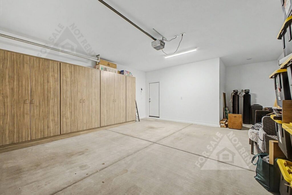 Custom garage at 18141 W Hiddenview Drive in Goodyear, Arizona, featuring built-in storage cabinets with ample space for tools, seasonal items, household supplies, and recreational equipment.